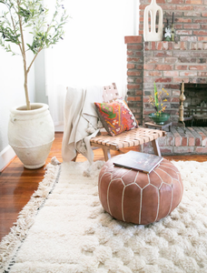 living room decorated with cream moroccan rugs, leather floor pouf and moroccan ceramics