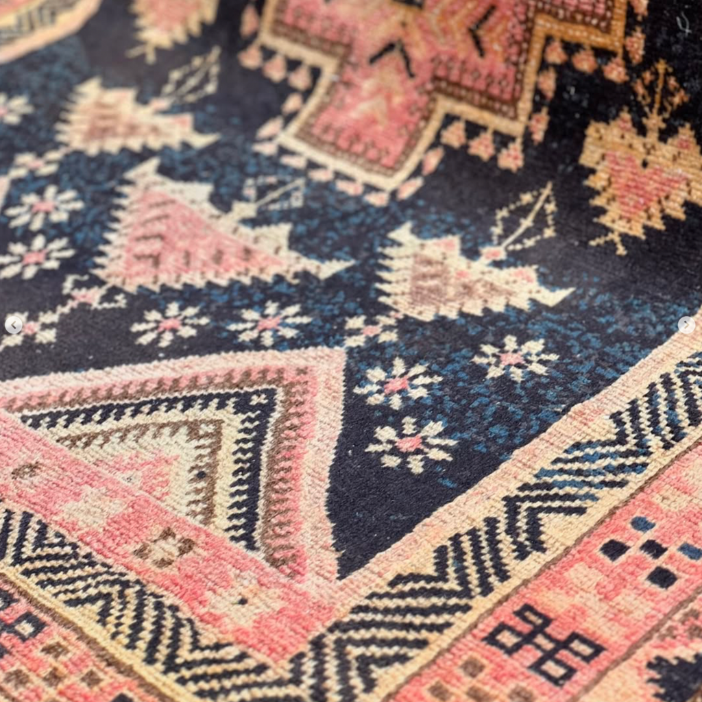 Close-up of a patterned rug with geometric designs in red, orange, and black.