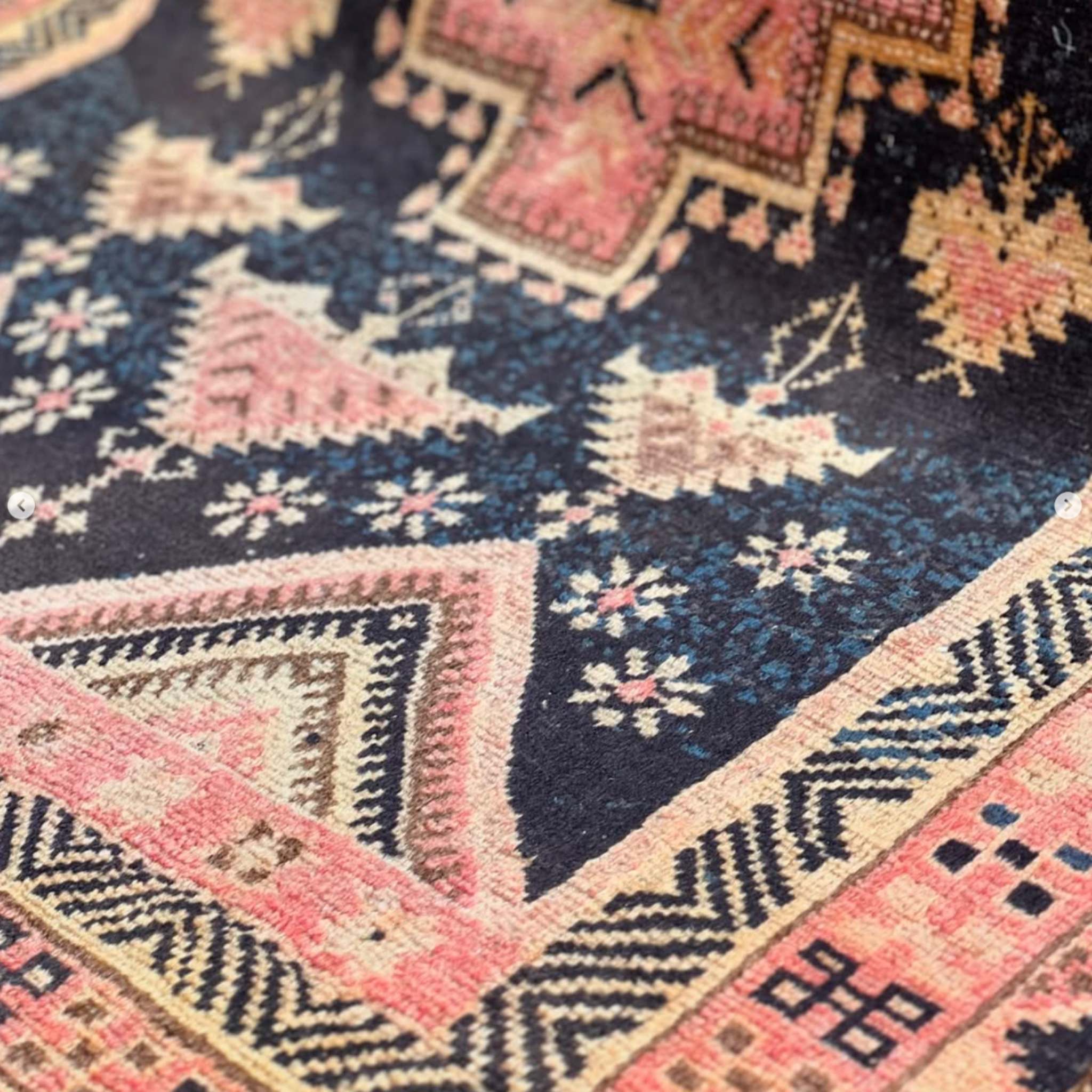 Close-up of a patterned rug with geometric designs in red, orange, and black.